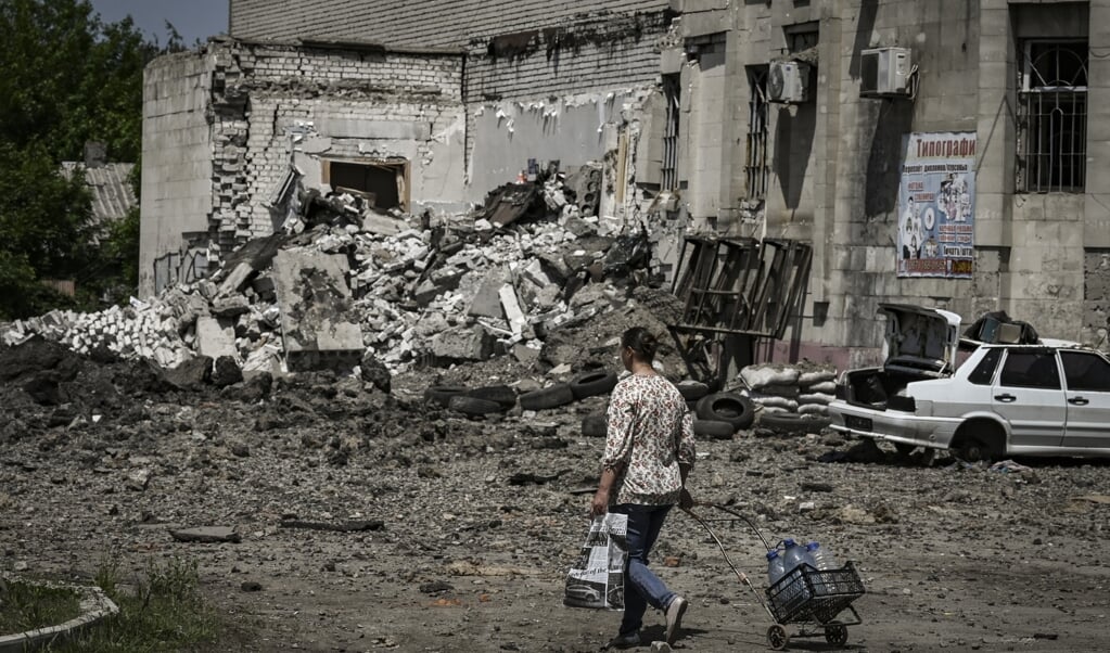 Een inwoner loopt langs de verwoestingen in de straten van Lysytsjansk.  (beeld afp / Aris Messinis)