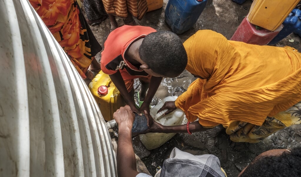 Mensen die hun huizen zijn ontvlucht vanwege de droogte vullen in de Ethiopische regio Afar hun jerrycan bij een watertank van een vluchtelingenkamp.  (beeld eduardo Soteras / afp)