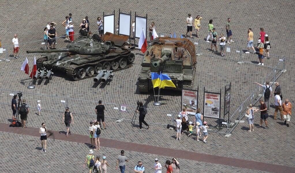 Toeristen lopen langs het vernietigde Russische oorlogstuig dat tentoongesteld staat in het centrum van Warschau.  (beeld ap / Michal Dyjuk)