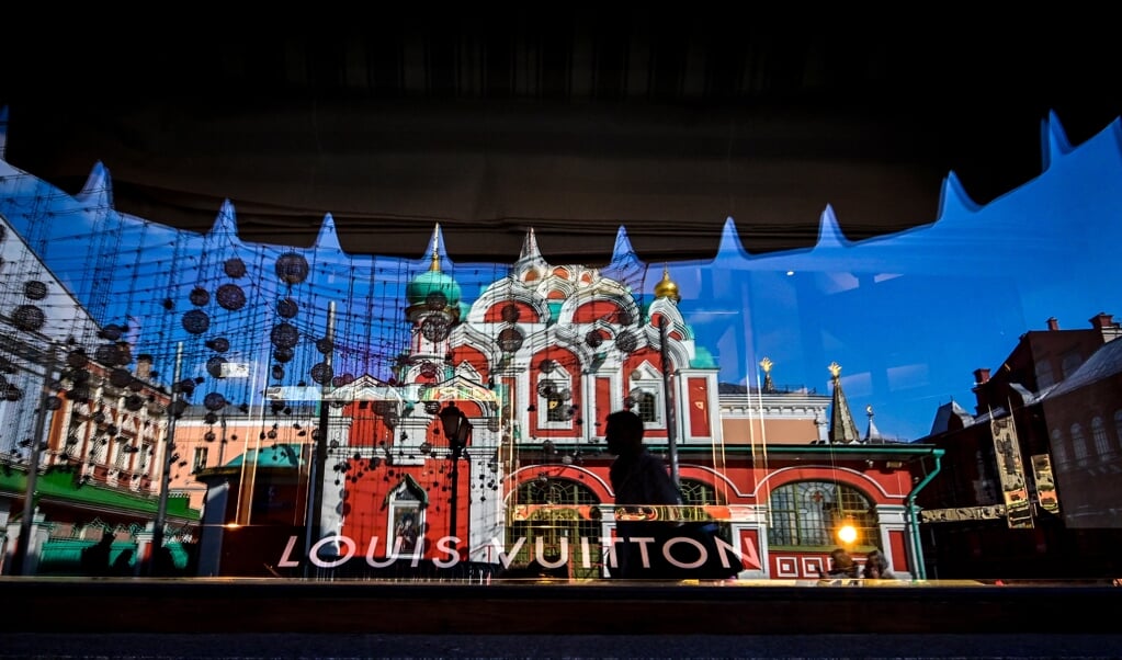 Een Russisch-orthodoxe kerk in Moskou, weerspiegeld in een het raam van een gesloten verkooppunt van Vuitton boutique in het warenhuis GUM. Talloze westerse bedrijven zijn uit Rusland vertrokken.   (beeld afp)