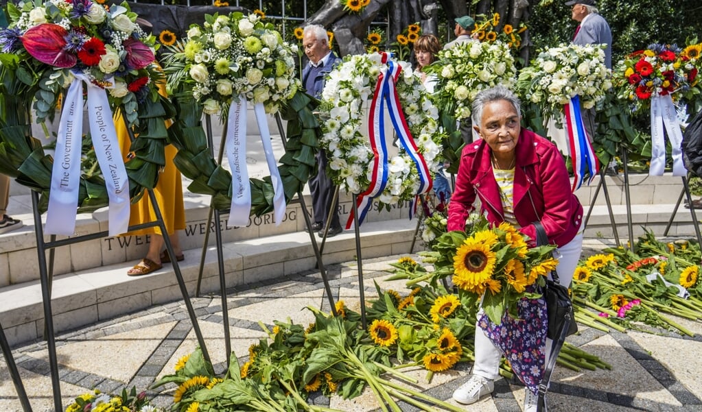 Genodigden leggen zonnebloemen bij het Indisch Monument tijdens de Nationale Herdenking van het einde van de Tweede Wereldoorlog in voormalig Nederlands-Indië (beeld anp / Jerry Lampen)