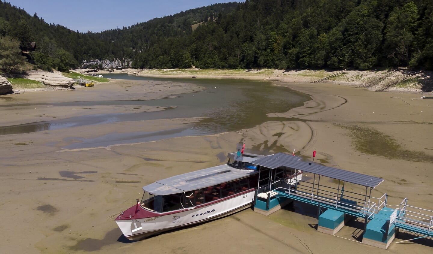 Een toeristenboot ligt vast in de drooggevallen bedding van de Doubs, die normaal tussen Frankrijk en Zwitserland stroomt.