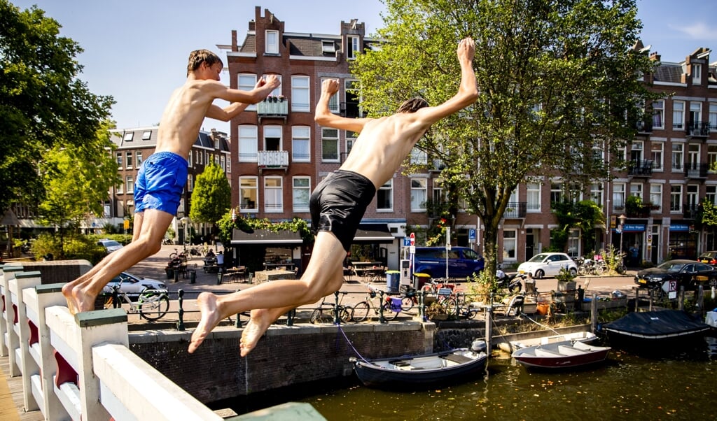 Gemeenten gaan strenger handhaven op wildzwemmen. Verkoeling zoeken in een gracht, zoals de jongens op de foto, kan binnenkort waarschijnlijk niet meer (beeld anp / Remko de Waal)