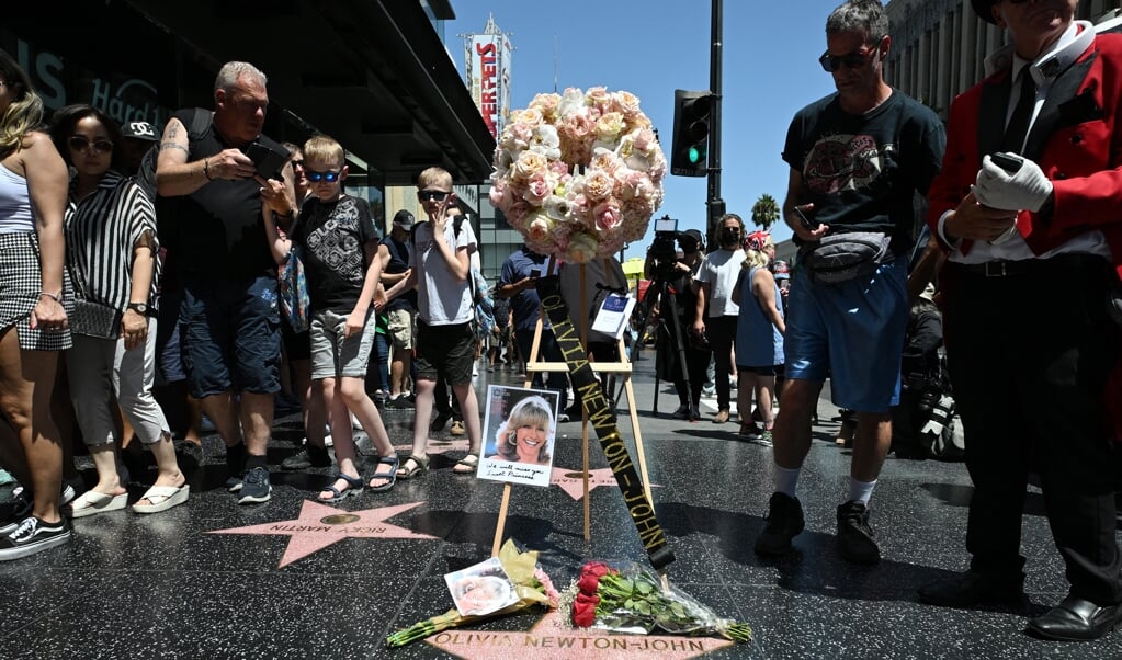 Fans leggen bloemen bij de ster van Olivia Newton-John op de Walk of Fame.  (beeld anp)