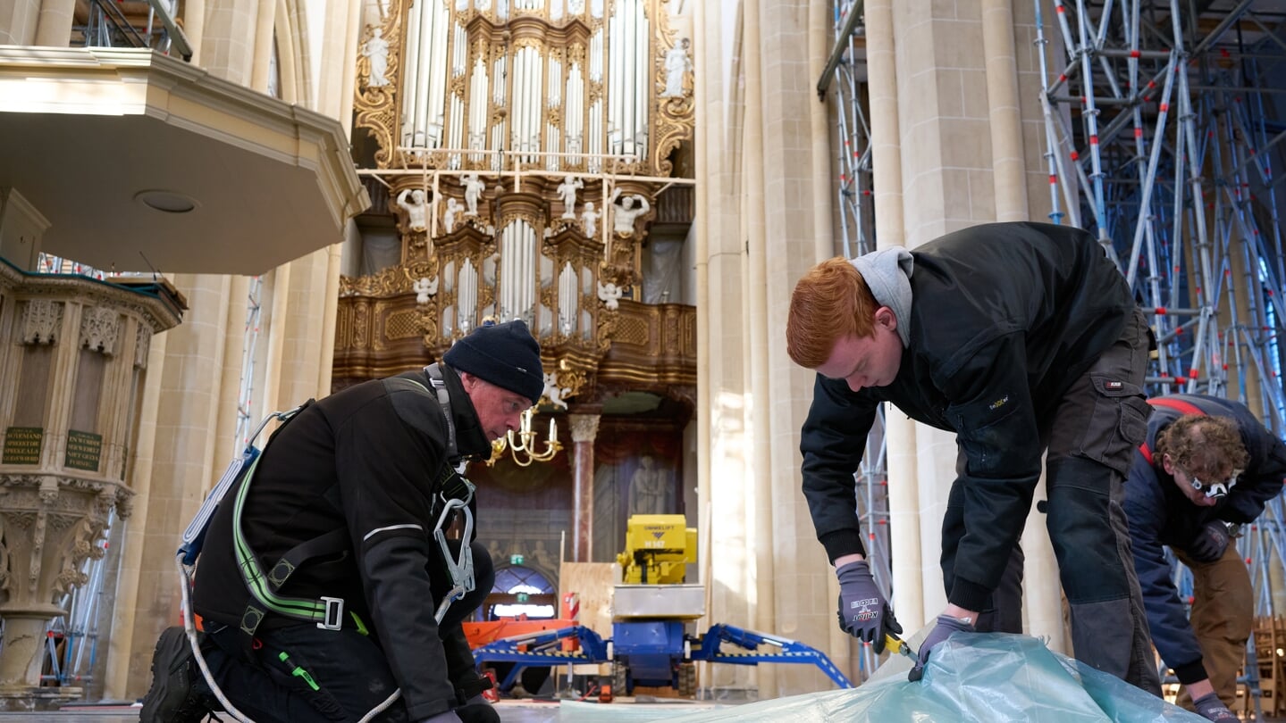 Orgelbouwers snijden plastic om het orgel in de Bovenkerk in Kampen mee te beschermen tegen vallende brokstukken van het plafond. 