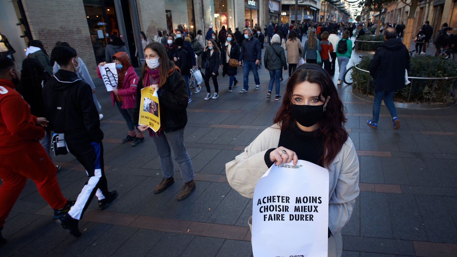 Een Franse vrouw demonstreert met Extinction Rebellion in een winkelstraat in de Franse stad Toulouse, om voorbijgangers bewust te maken van de gevolgen van 'fast fashion'. Op het papier dat ze vasthoudt, staat: Koop minder, kies beter, maak het duurzaam. 