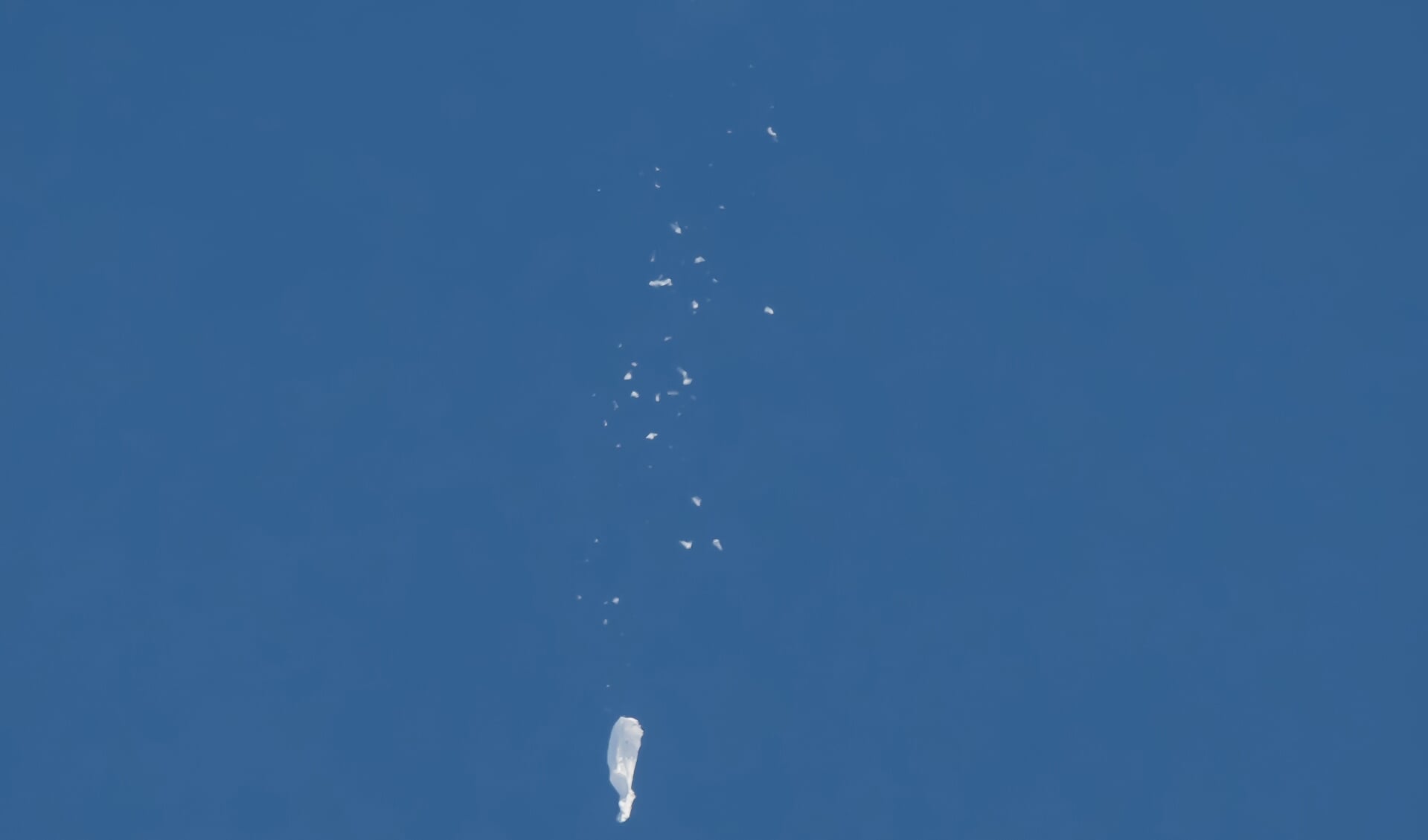 De Chinese ballon valt naar beneden, richting de oceaan, nadat de Verenigde Staten hem heeft neergeschoten.