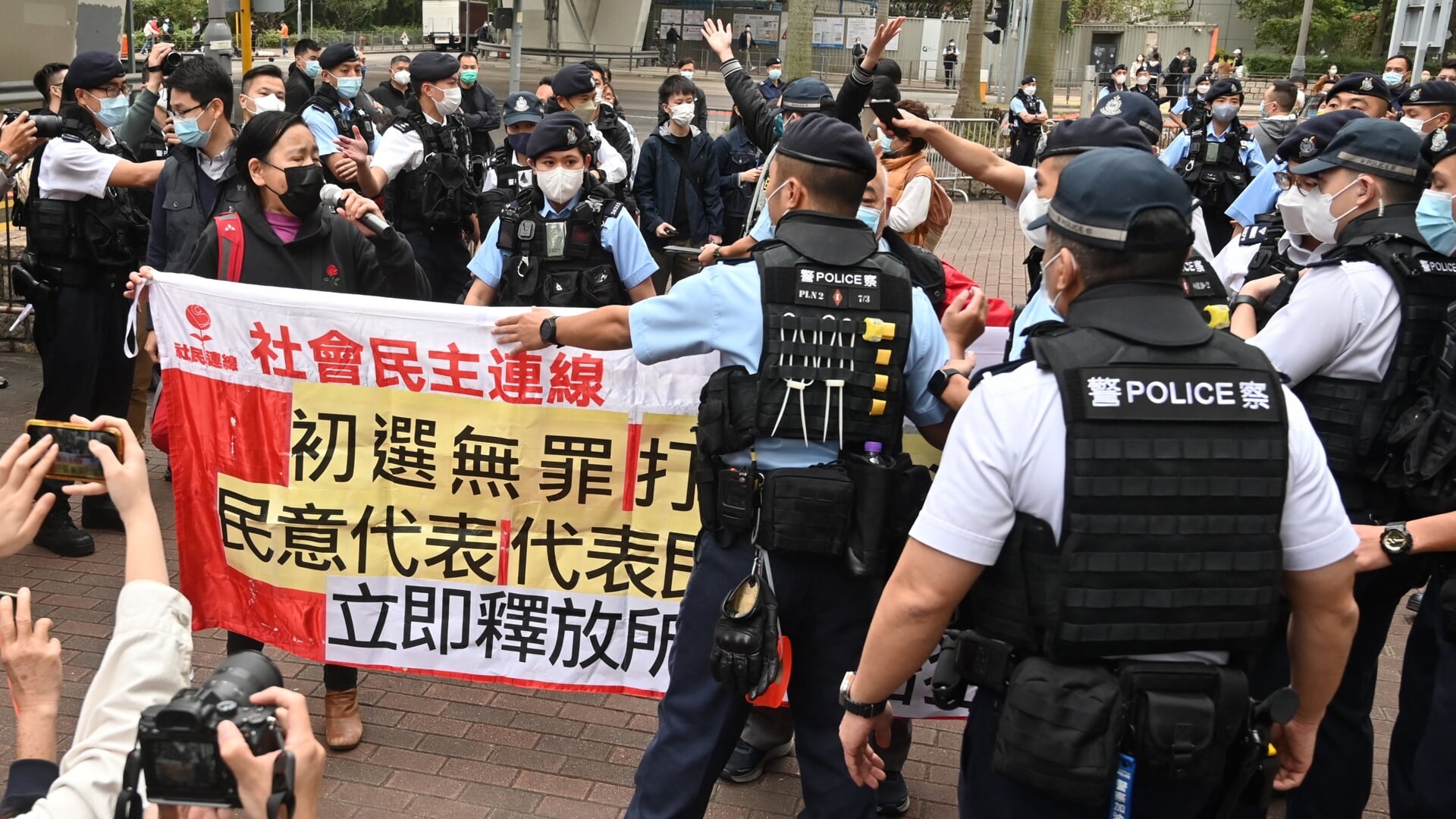 Politieagenten omsingelen leden van de Bond van Sociaal-Democraten die protesteren tegen de berechting van 47 prodemocratische activisten.