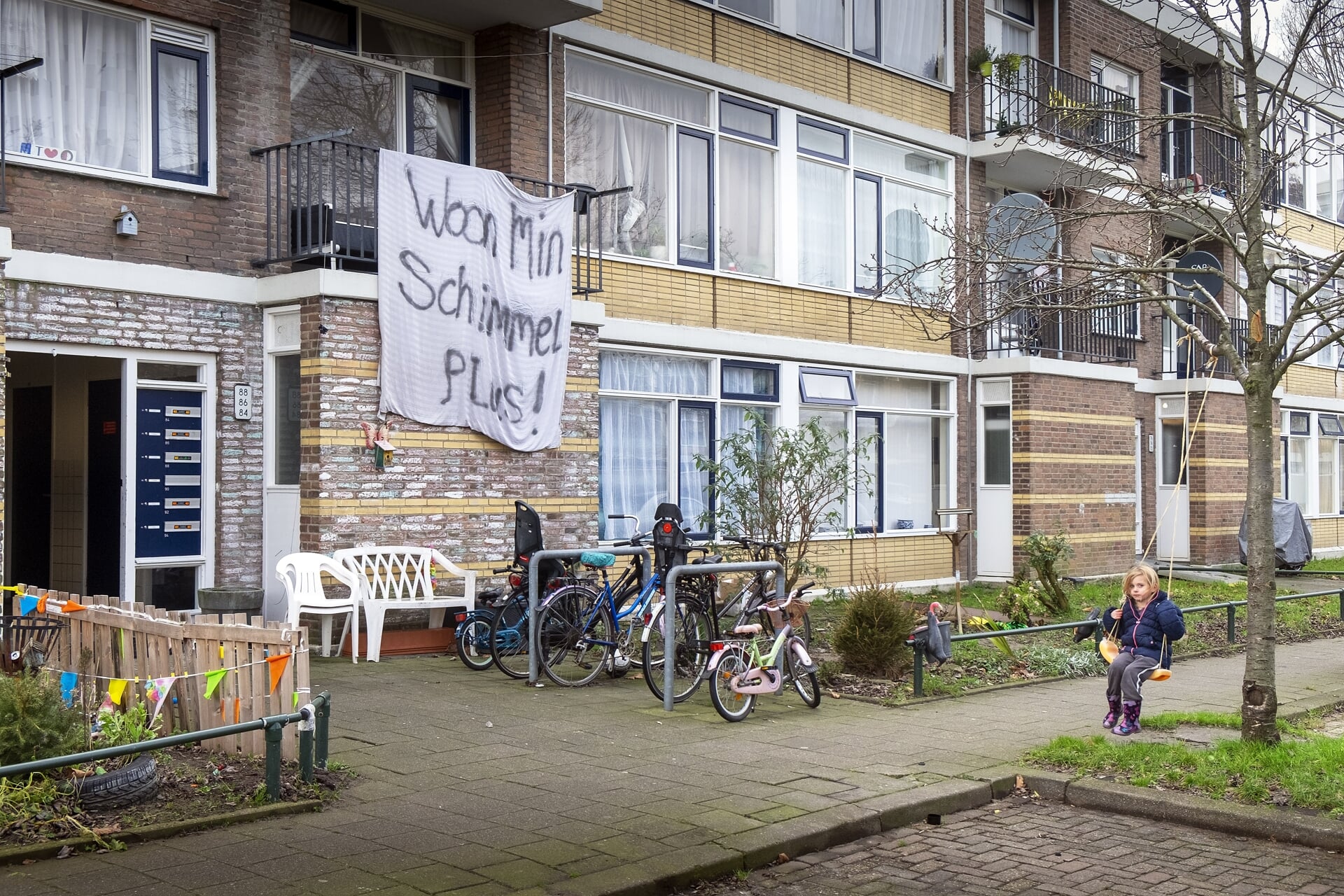 Protest tegen achterstallig onderhoud van woningen in de Staatsliedenbuurt in Schiedam met de leus 'Woon min schimmel plus'.
