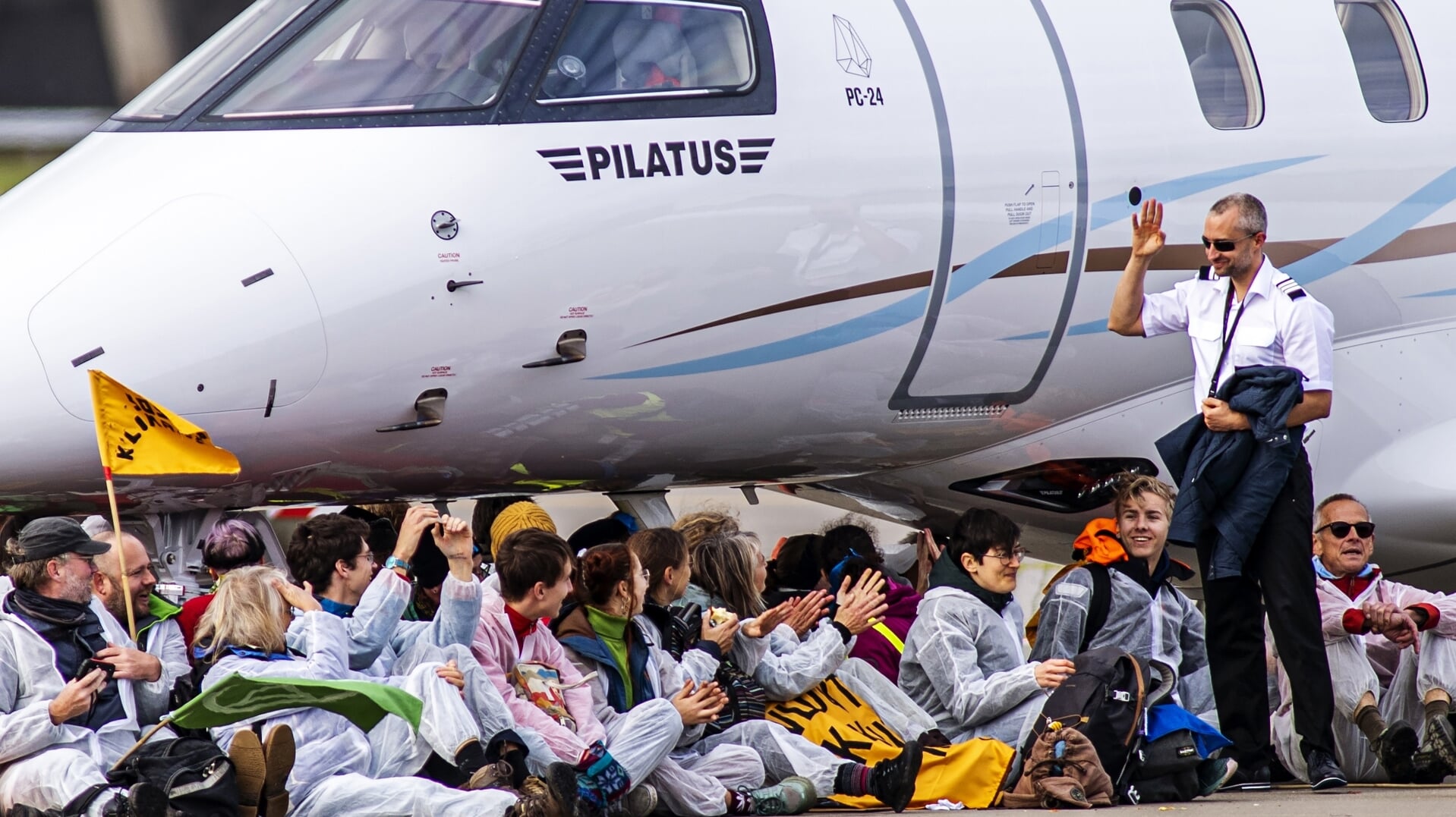 Een piloot stapt uit zijn privéjet en zwaait naar klimaatactivisten die in november het gedeelte op vliegveld Schiphol waar privévliegtuigen staan bezetten. Zaterdag voeren wetenschappers van Scientist Rebellion actie op Eindhoven Airport. 'Het is een overbodige manier van reizen waarmee een kleine elite buitenproportioneel bijdraagt aan de CO2-uitstoot.'