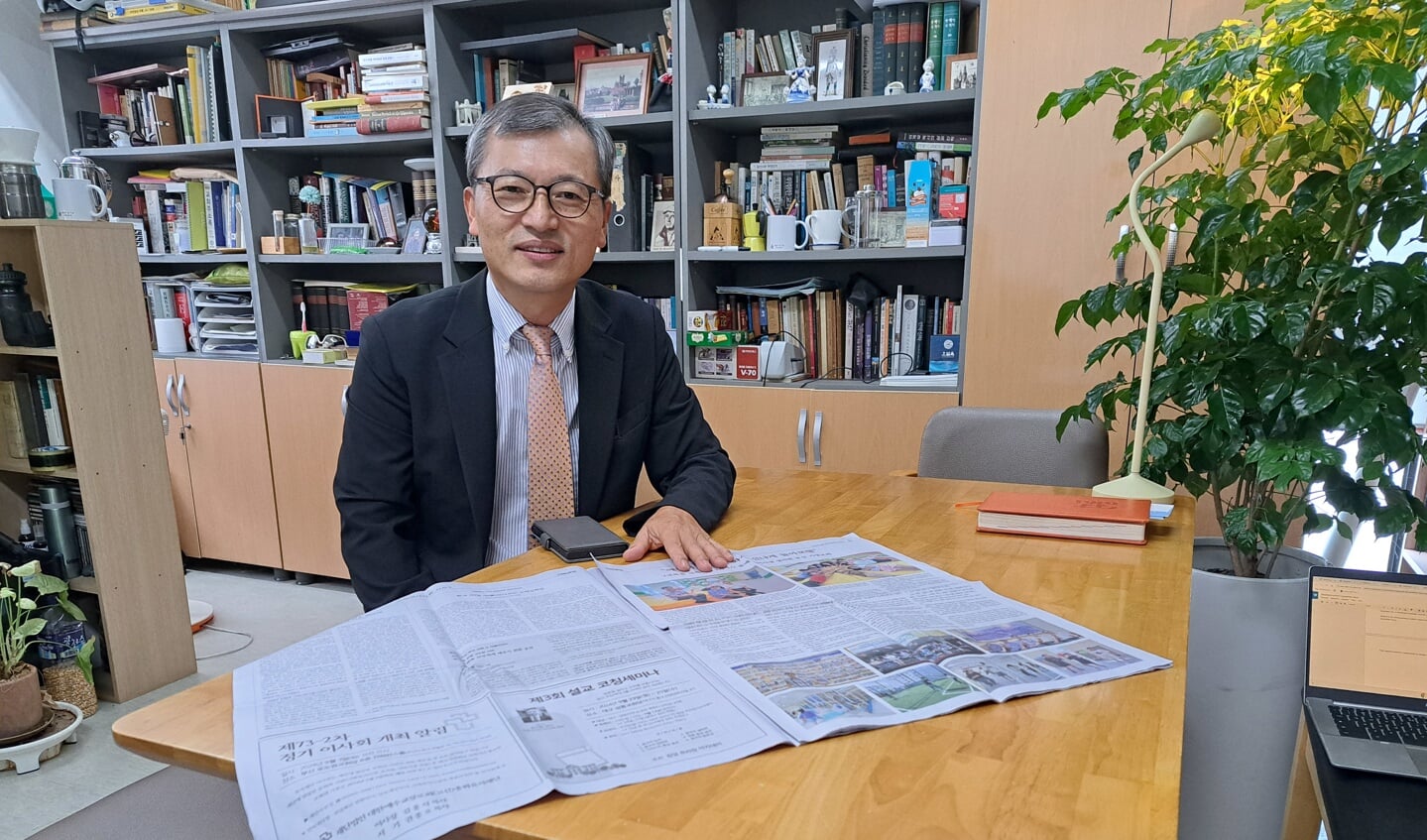 Dominee Koen Lim met de krant waarin hij al veertig weken schrijft over de geschiedenis van de Kosin-kerk.