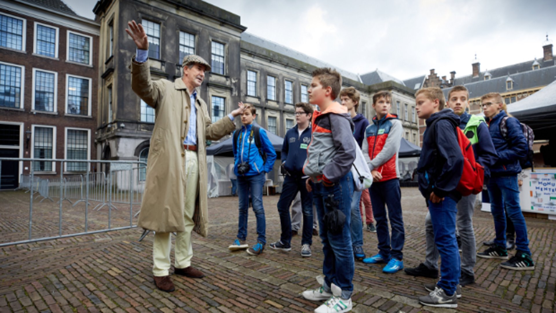 Menno de Bruyne, met Engelse pet, leidt een groep kinderen rond op het inmiddels gesloten Binnenhof. 'Als de Kamer niet vergaderde, was de kans groot dat je Menno zag rondlopen.'