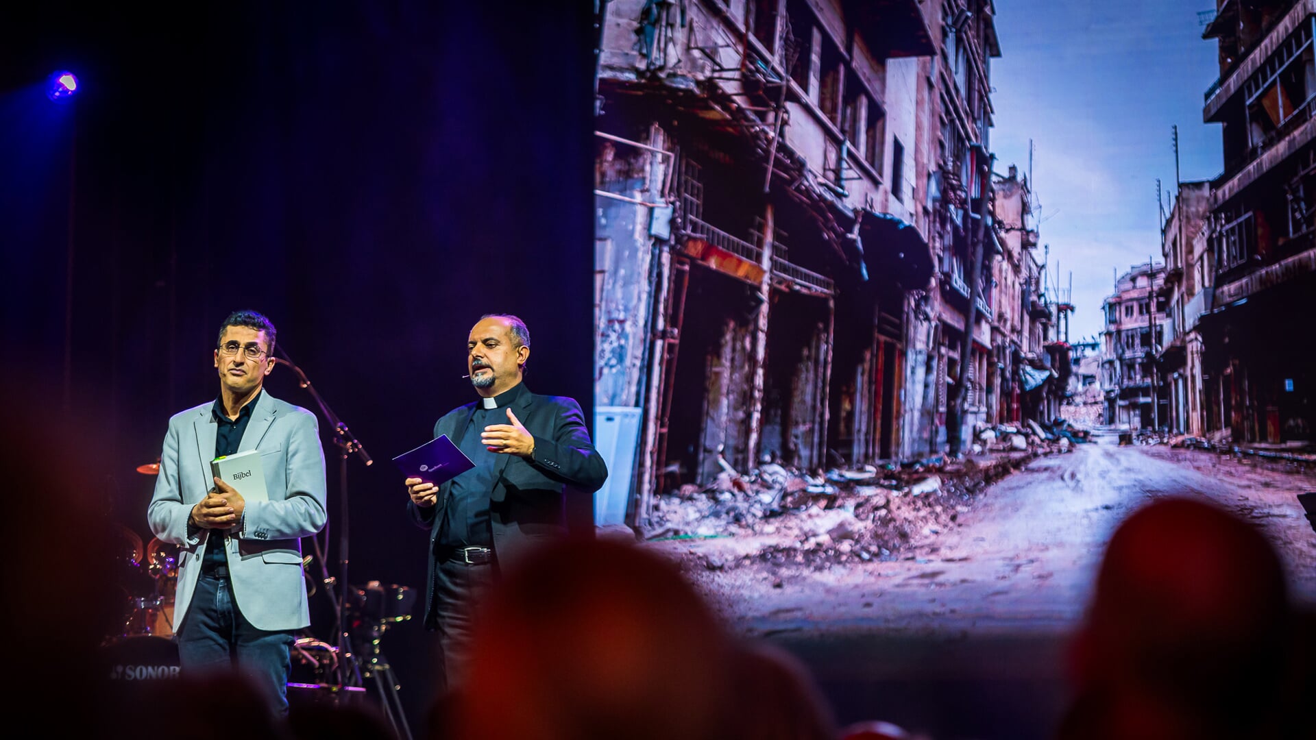 Pastor George uit Syrië (rechts) vertelt hoe hij met zijn gezin heeft geleden onder de oorlog in zijn land. ‘De Jezus die met ons is in de oorlog, is ook in vredestijd met ons. Volg hem. Laat je niet opslokken door alledaagse bezigheden.'