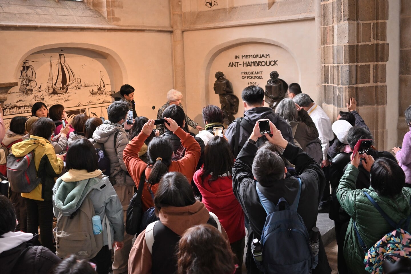 De Taiwanese bezoekers verdringen zich met hun camera's voor het herdenkingsmonument van Hambrouck in de Laurenskerk.