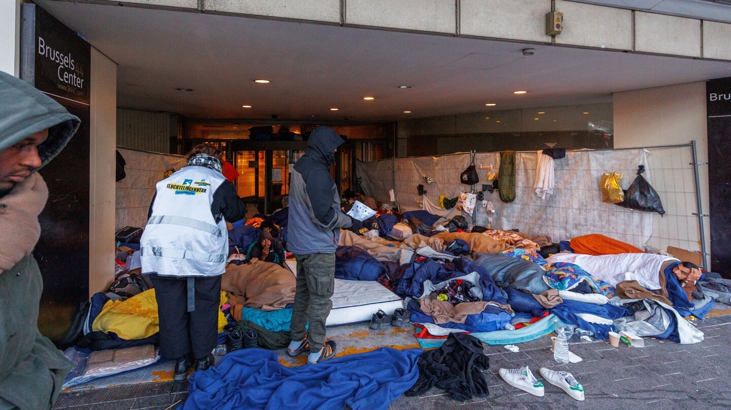 Asielzoekers slapen in de portiek van een leegstaand Brussels kantoor.