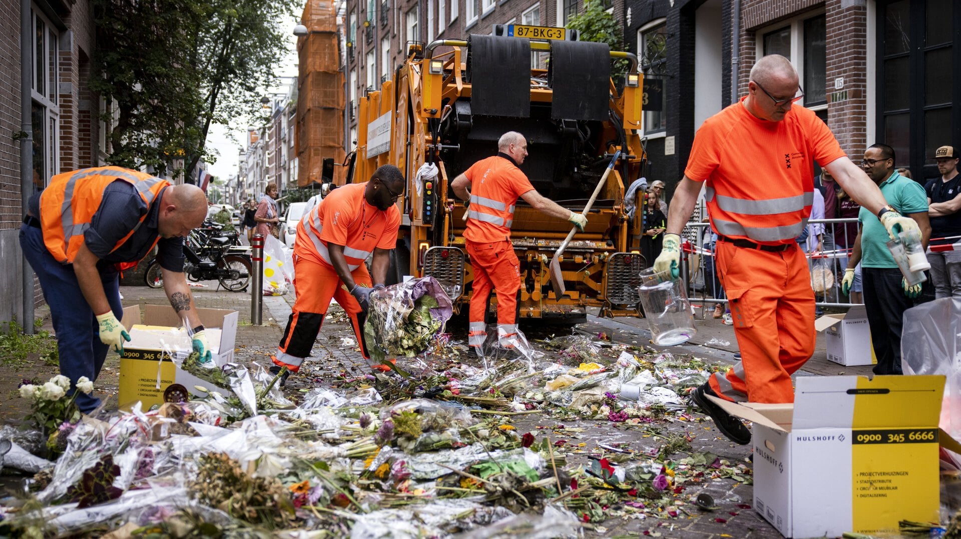 Medewerkers van de gemeente ruimen de bloemen en kaartjes op die voor Peter R. de Vries in de Lange Leidsedwarsstraat zijn neergelegd.
