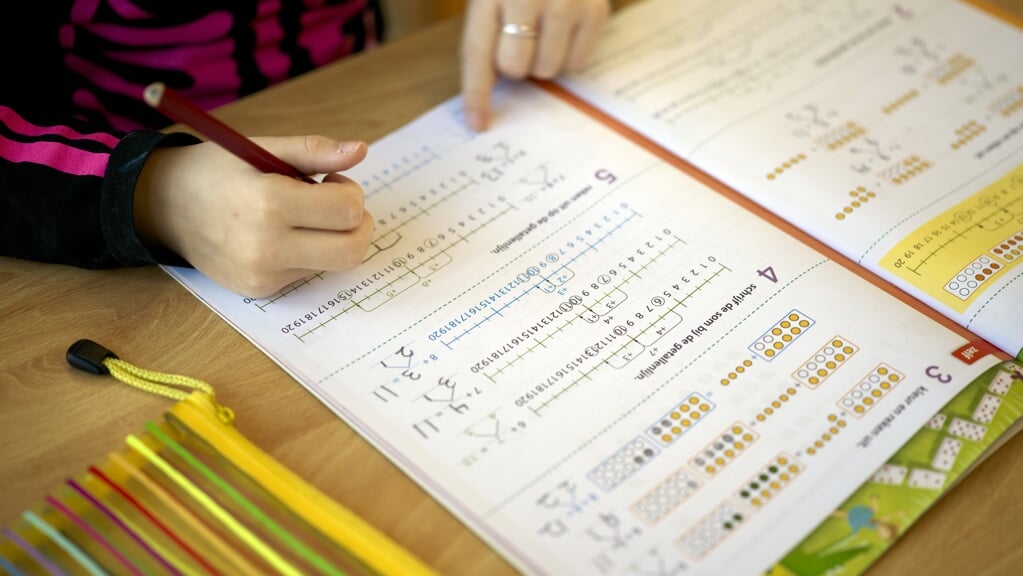 Een leerling is aan het werk in een werkschrift rekenen op de basisschool.