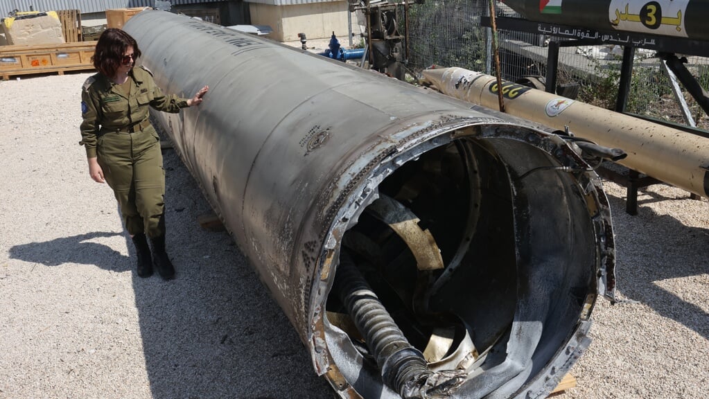 Een lid van het Israëlische leger staat naast een Iraanse ballistische raket die in het weekend in Israël is gevallen.