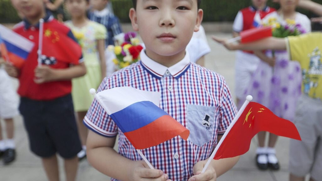 Chinees jongetje zwaait met de Russische en Chinese vlag bij een staatsbezoek van Vladimir Poetin aan Peking.