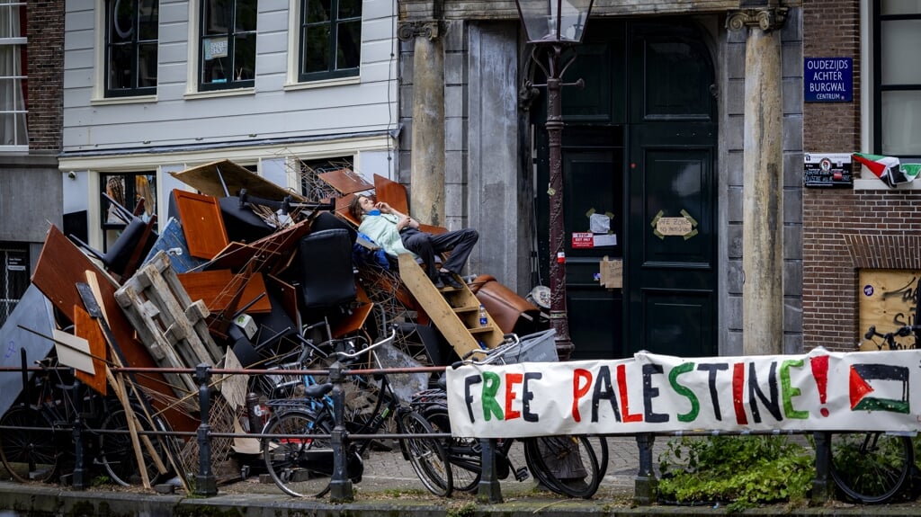 Een demonstrant houdt de wacht op een van de barricades bij het Binnengasthuisterrein van de Universiteit van Amsterdam. Pro-Palestijnse betogers hebben de nacht van dinsdag op woensdag doorgebracht achter door hen opgeworpen barricades op het terrein.
