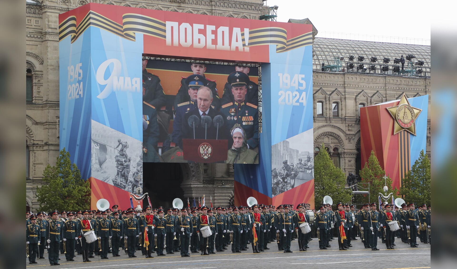 Via een groot scherm is de jaarlijkse toespraak van president Vladimir Poetin op het Rode Plein in Rusland te volgen. 