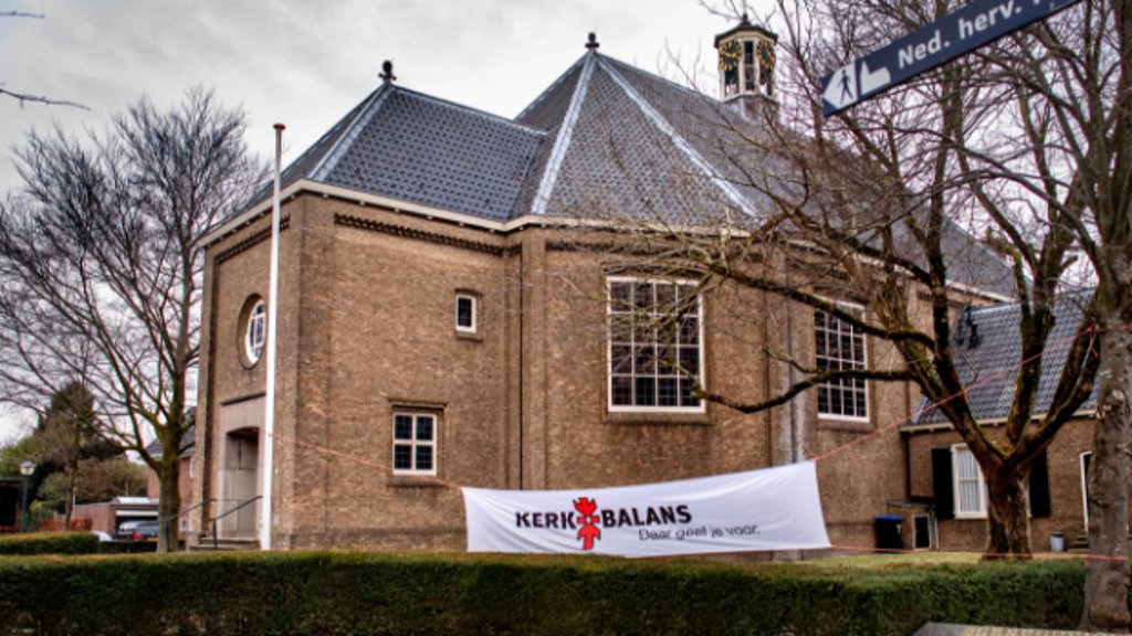Spandoek voor de Actie Kerkbalans in Klundert om geld in te zamelen voor de kerk. Kerken en goede doelen vrezen dat Nederlanders minder geld gaan geven als dat straks fiscaal minder aantrekkelijk wordt.