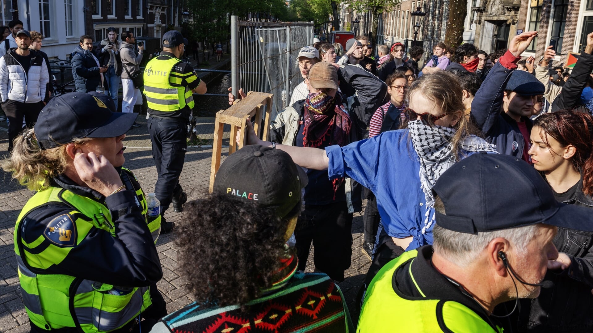 Demonstranten staan voor de deur van het Binnengasthuis van de Universiteit van Amsterdam.