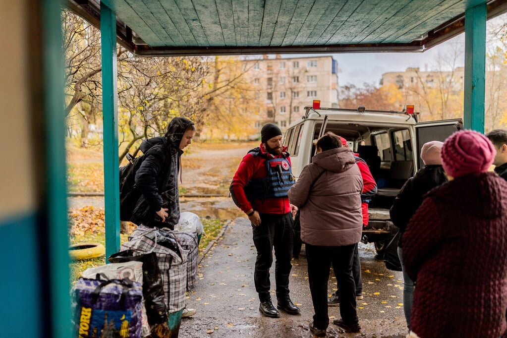 Burgers in Charkiv wachten bij een auto van het Rode Kruis.