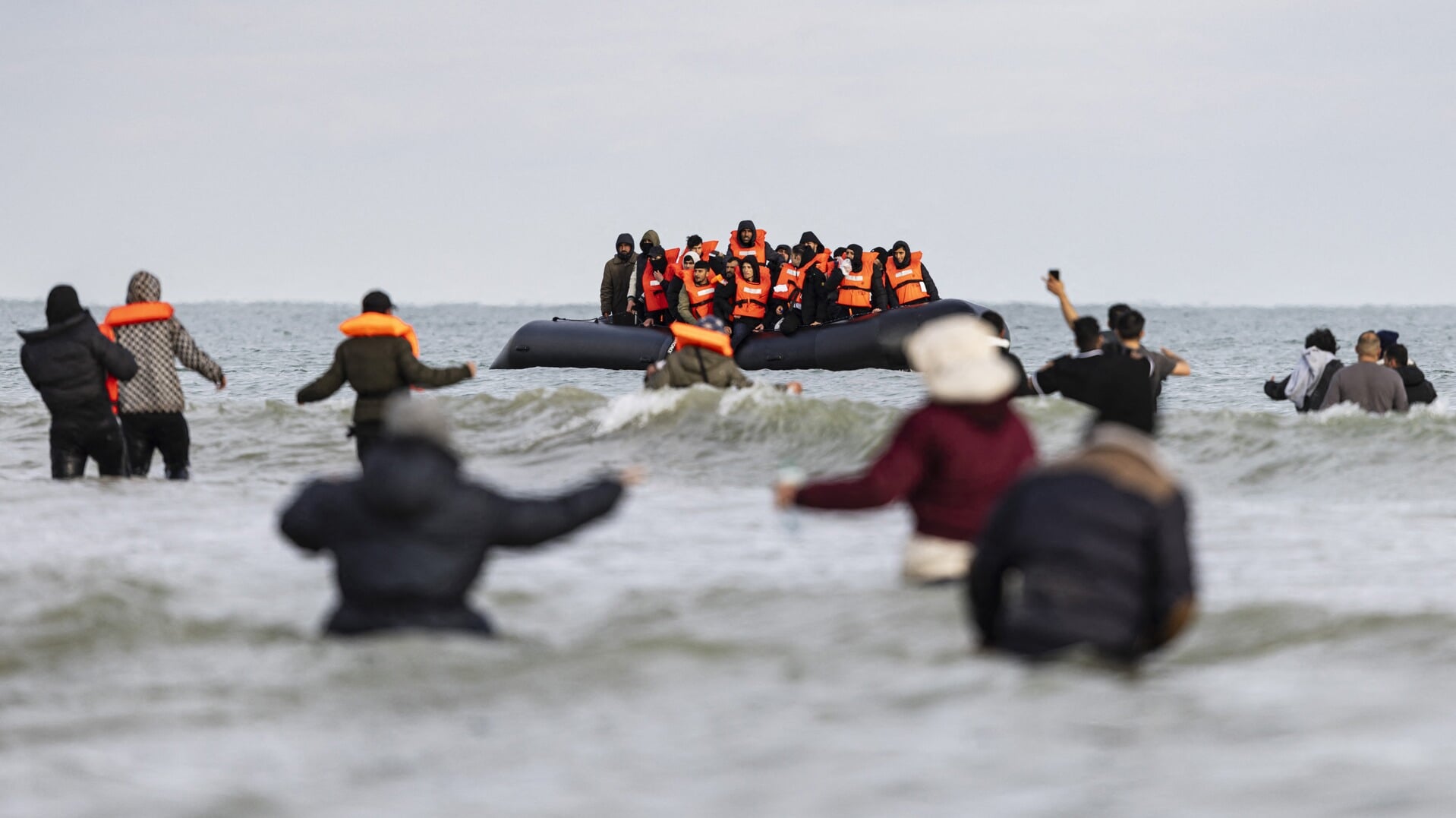 Asielzoekers proberen aan boord te komen van een rubberboot, aan de kust tussen Calais en Duinkerke.
