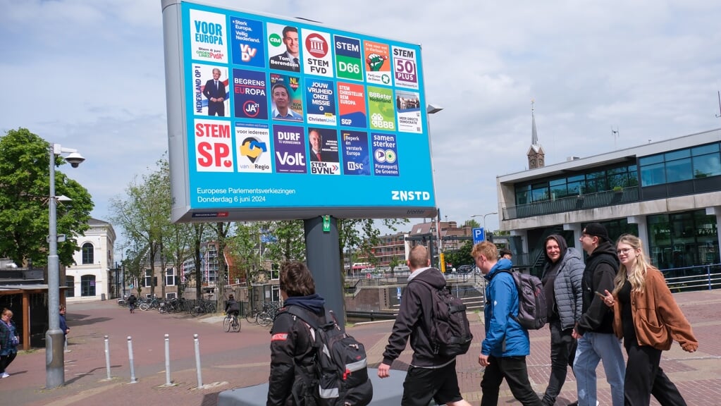 Jongeren lopen langs een bord met posters van politieke partijen voor de Europese Parlementsverkiezingen op 6 juni 2024.