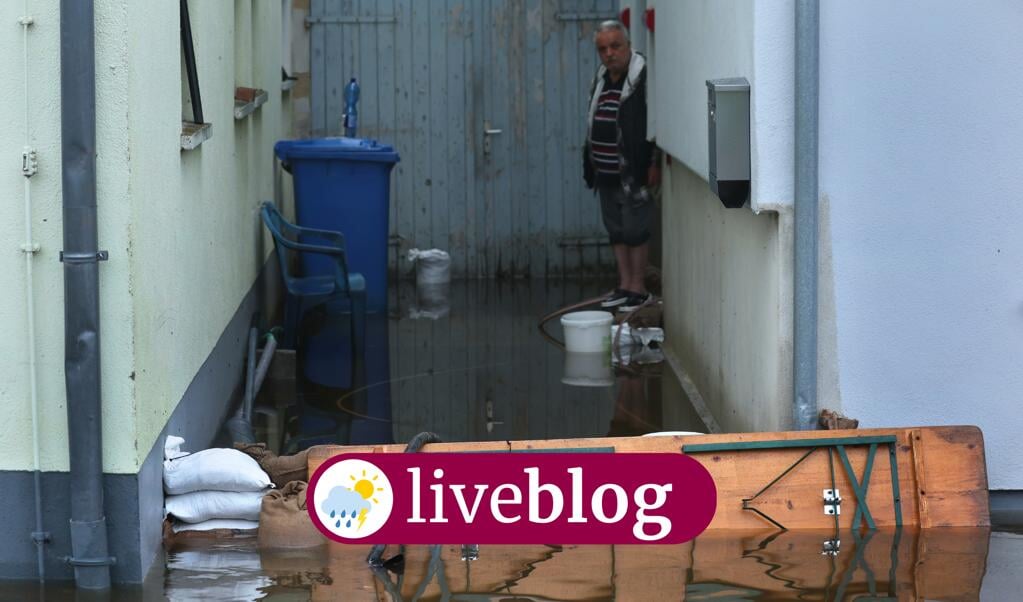Wateroverlast in Beieren. Deze man probeert zijn huis te beschermen tegen de overstroming.