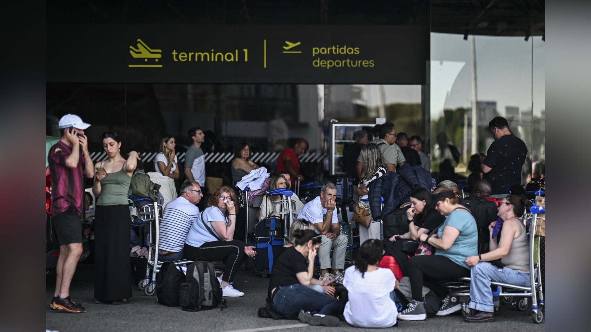 Buiten de luchthaven in Lissabon wachten mensen tot hun vliegtuig vertrekt.