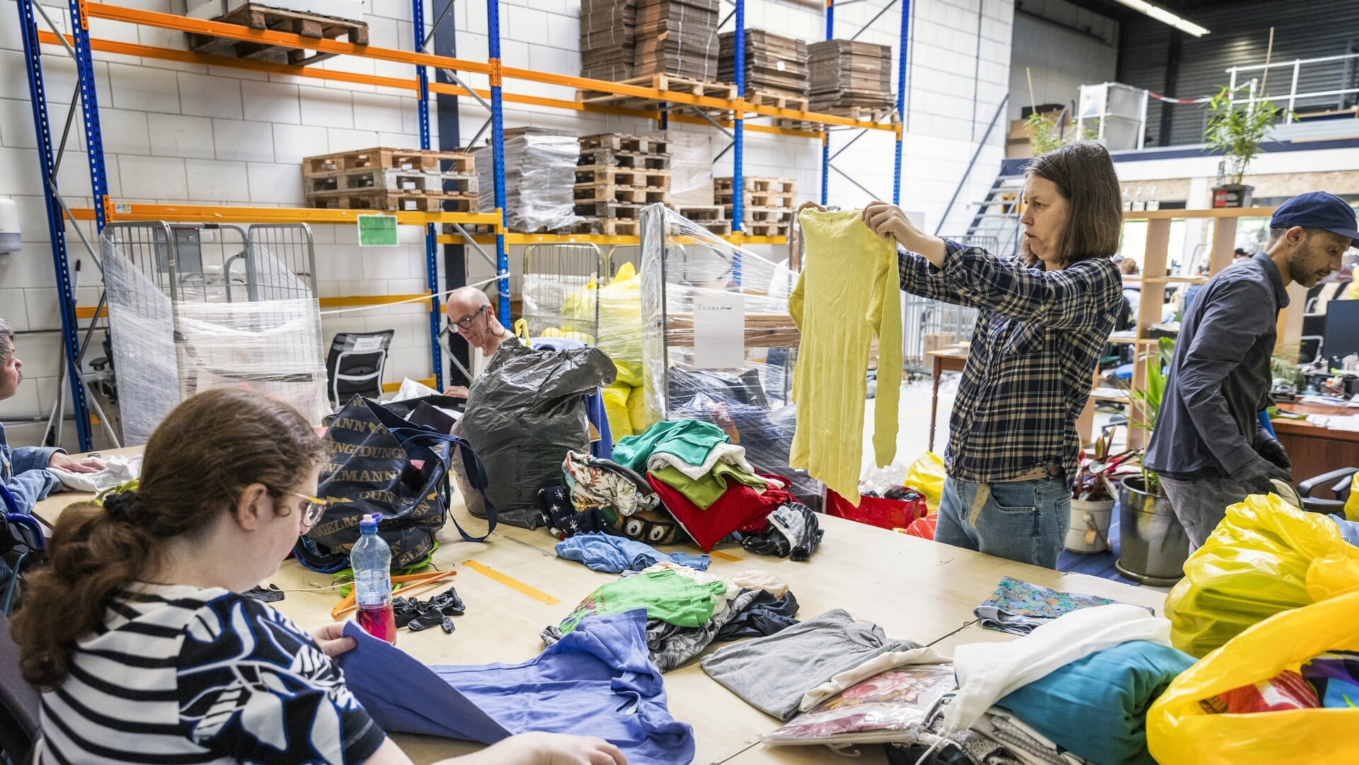 Medewerkers zoeken kleding uit in Schroeder Kringloop en buurtcentrum in Den Haag.
