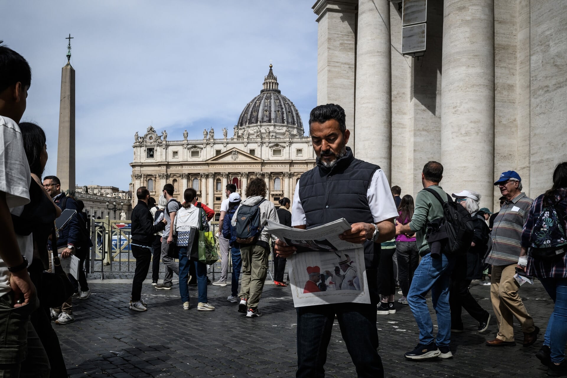 Bezoekers van het SInt-Pietersplein lezen een speciale editie van de Vaticaanse krant over de verkiezing van de nieuwe paus.