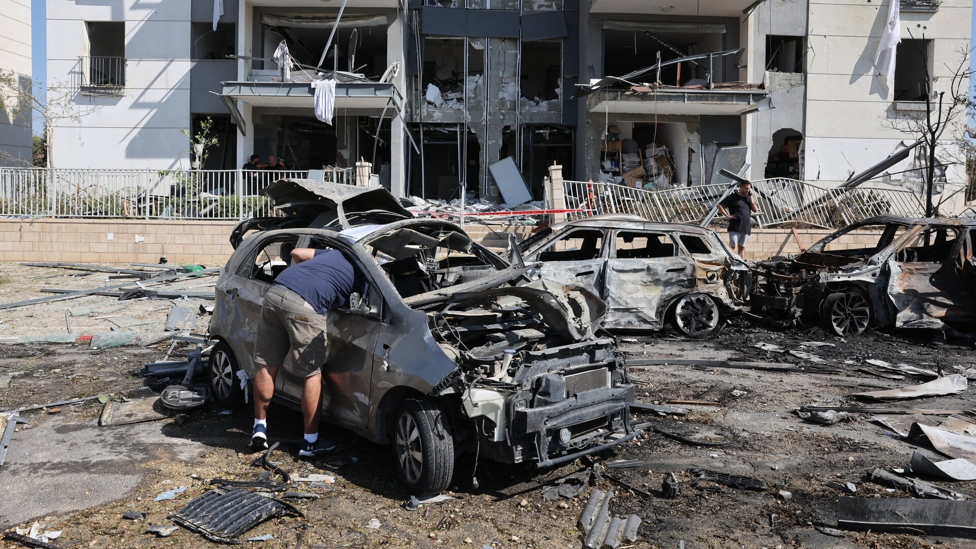 Een man onderzoekt zijn auto bij het getroffen appartementencomplex in de Israëlische stad Beër Sjeva na een raketaanval van Iran.