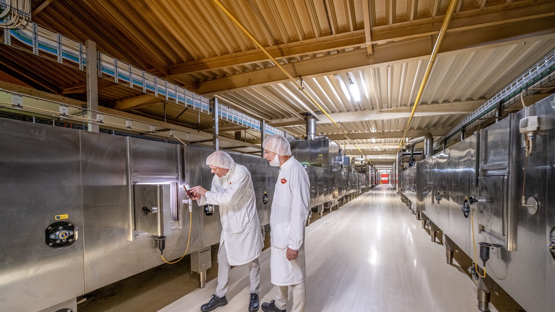 Hille en Gerrit Hellema in hun fabriek te Hallum bij de koekjesovens.