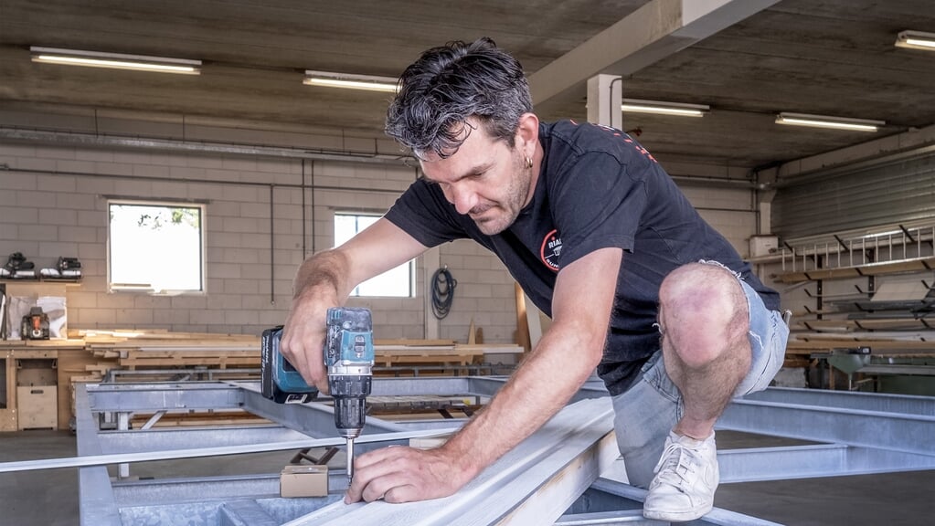 Zoon en eigenaar Rick de Wildt werkt aan het onderstel van een strandhuisje.