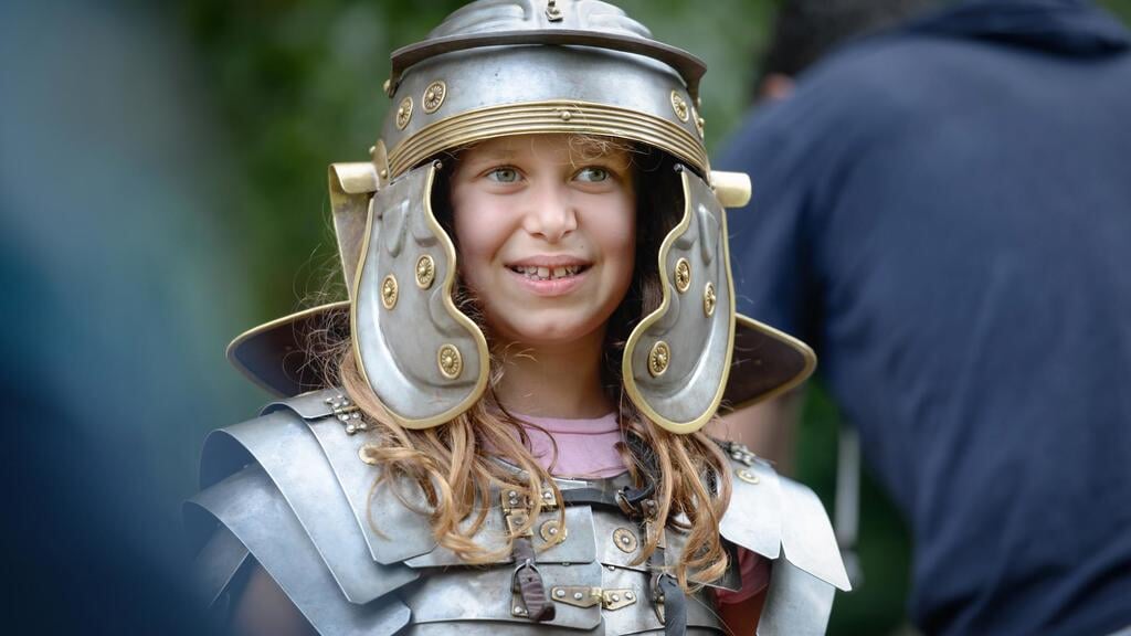 Kinderen mogen in Museumpark Archeon in Alphen aan den Rijn een Romeinse helm passen.
