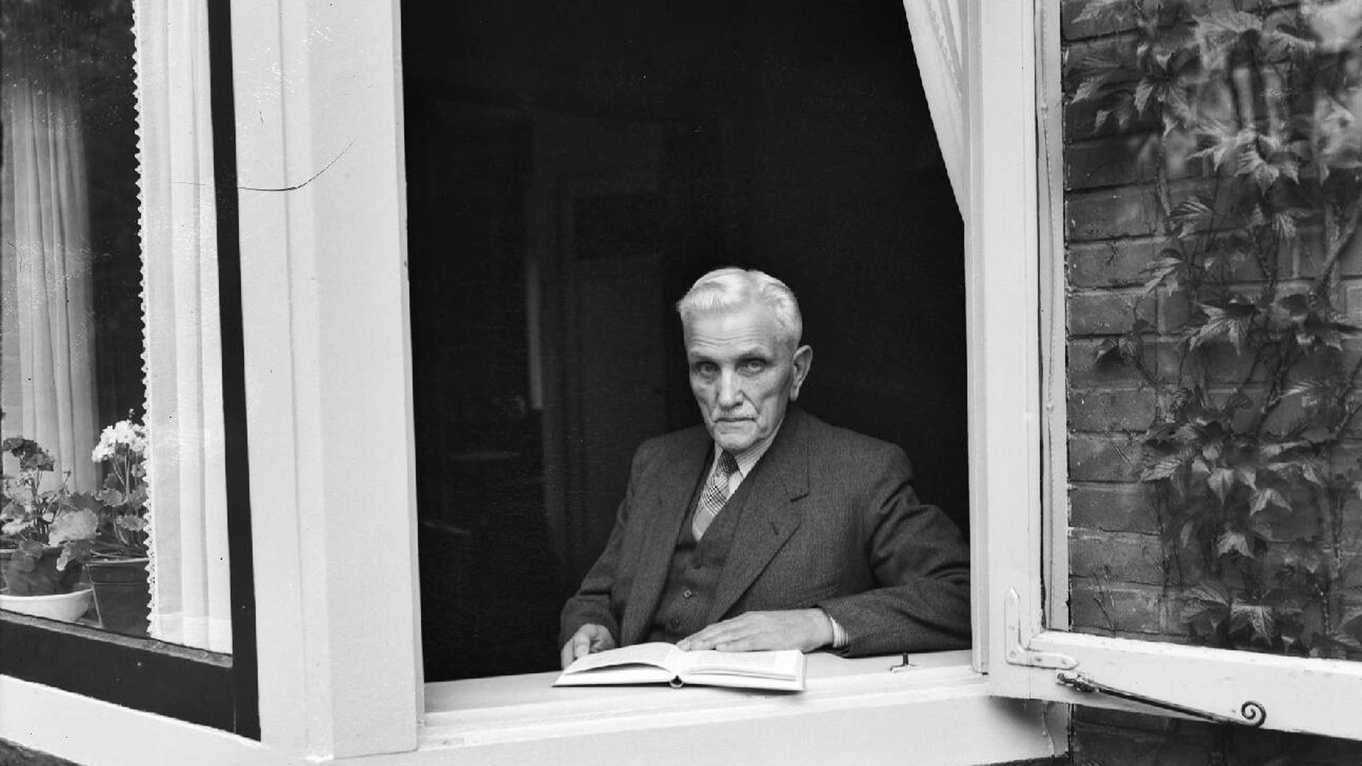 Johannes de Heer poseert in 1951 op 85-jarige leeftijd voor het raam van zijn woning in Driebergen.