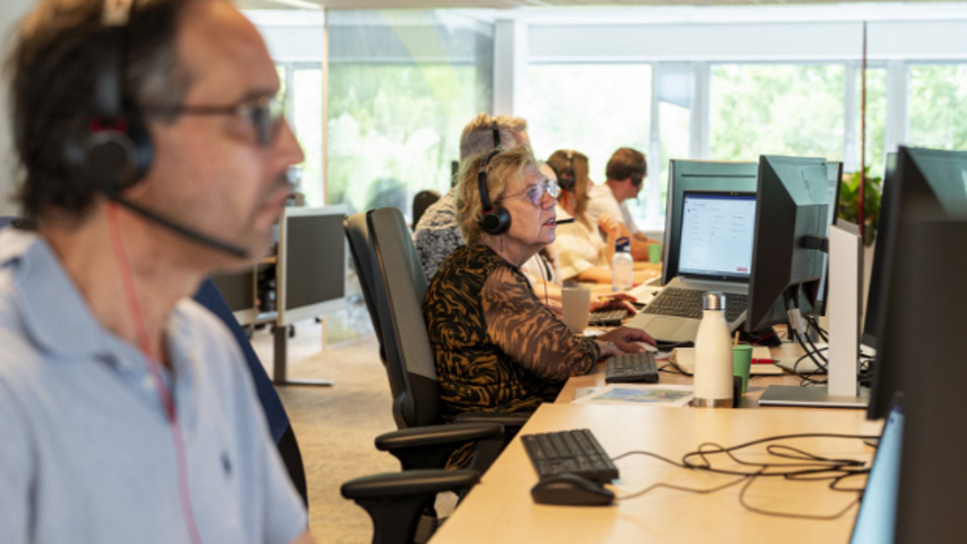 Medewerkers zittend aan het werk in de ANWB-alarmcentrale.