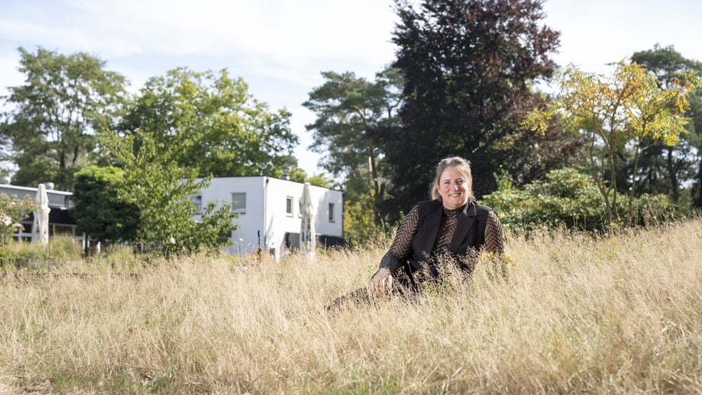 Dariëlle van Bemmel, parkmanager bij Landgoed Ginkelduin in Leersum, zit in het hoge gras bij de ingang van het vakantiepark. Ze heeft het maaibeleid aangepast nadat ze de training Natuurinclusief Ondernemen volgde. 