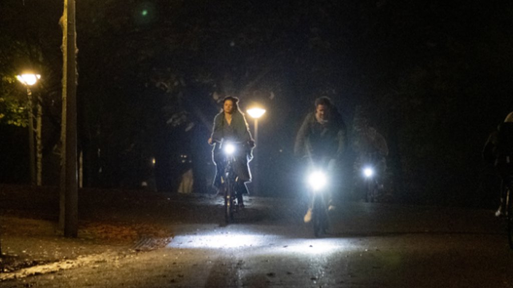 Fietsers in het donker met fietsverlichting en straatlantaarns in het Vondelpark.