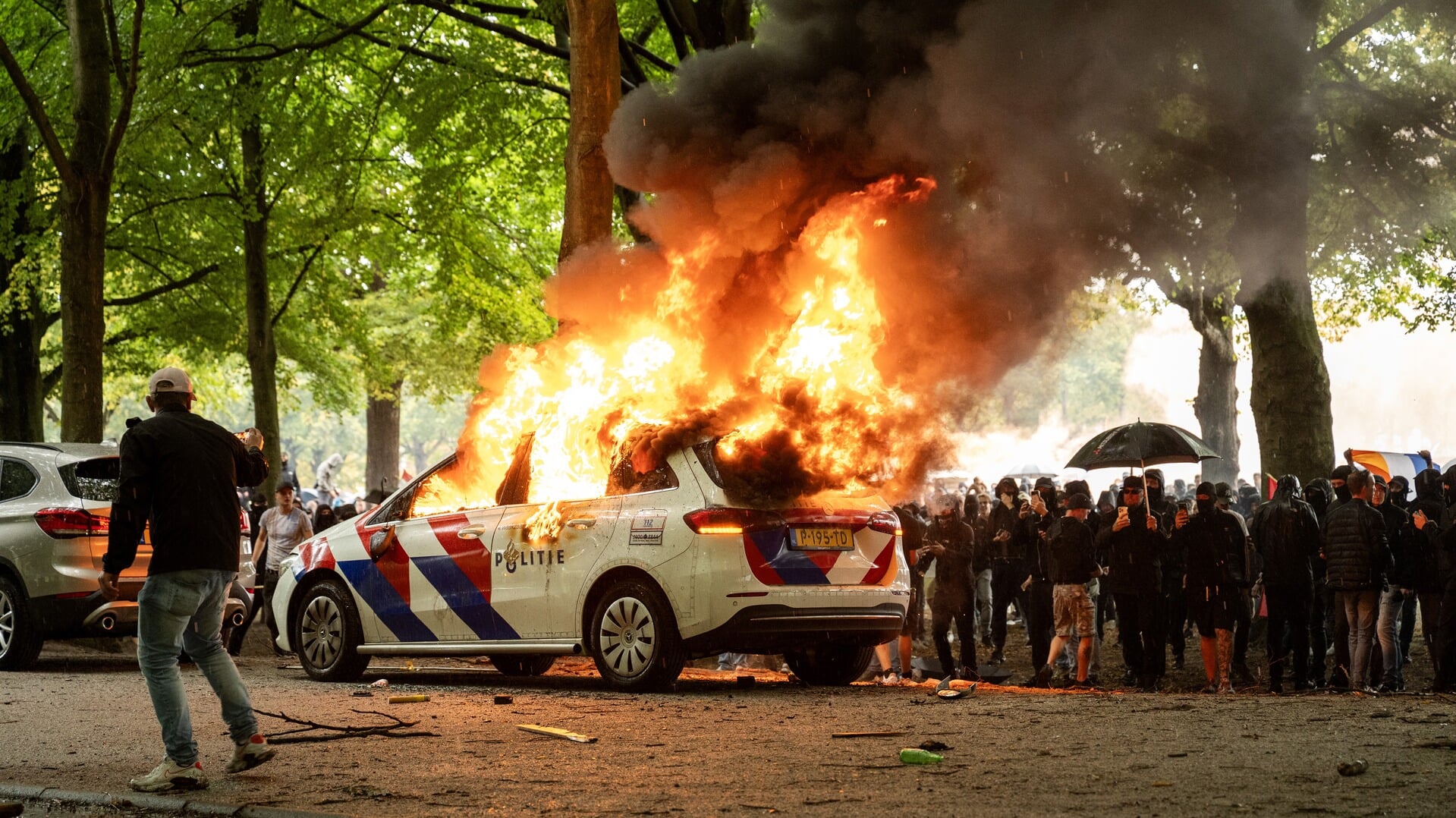 Politiewagen staat in brand bij de rellen rond het protest tegen het huidige asielbeleid op het Malieveld.