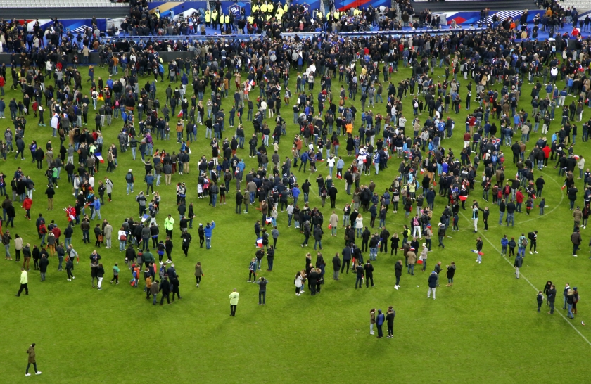 Voetbalsupporters stromen het veld op na de wedstrijd Frankrijk-Duitsland als ze horen van de aanslagen bij het stadion.