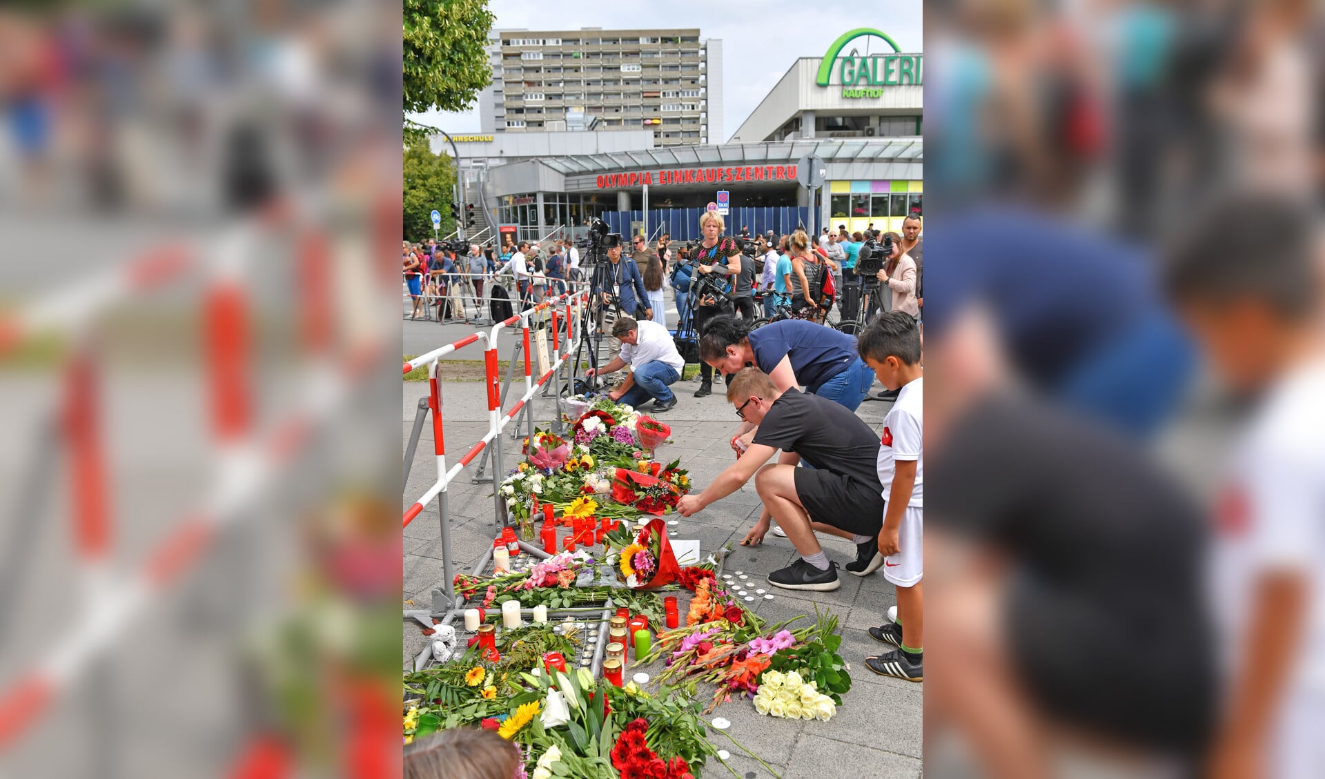 Meelevende burgers leggen bloemen en plaatsen kaarsen buiten het winkelcentrum waar de schietpartij vrijdagavond plaatsvond.
