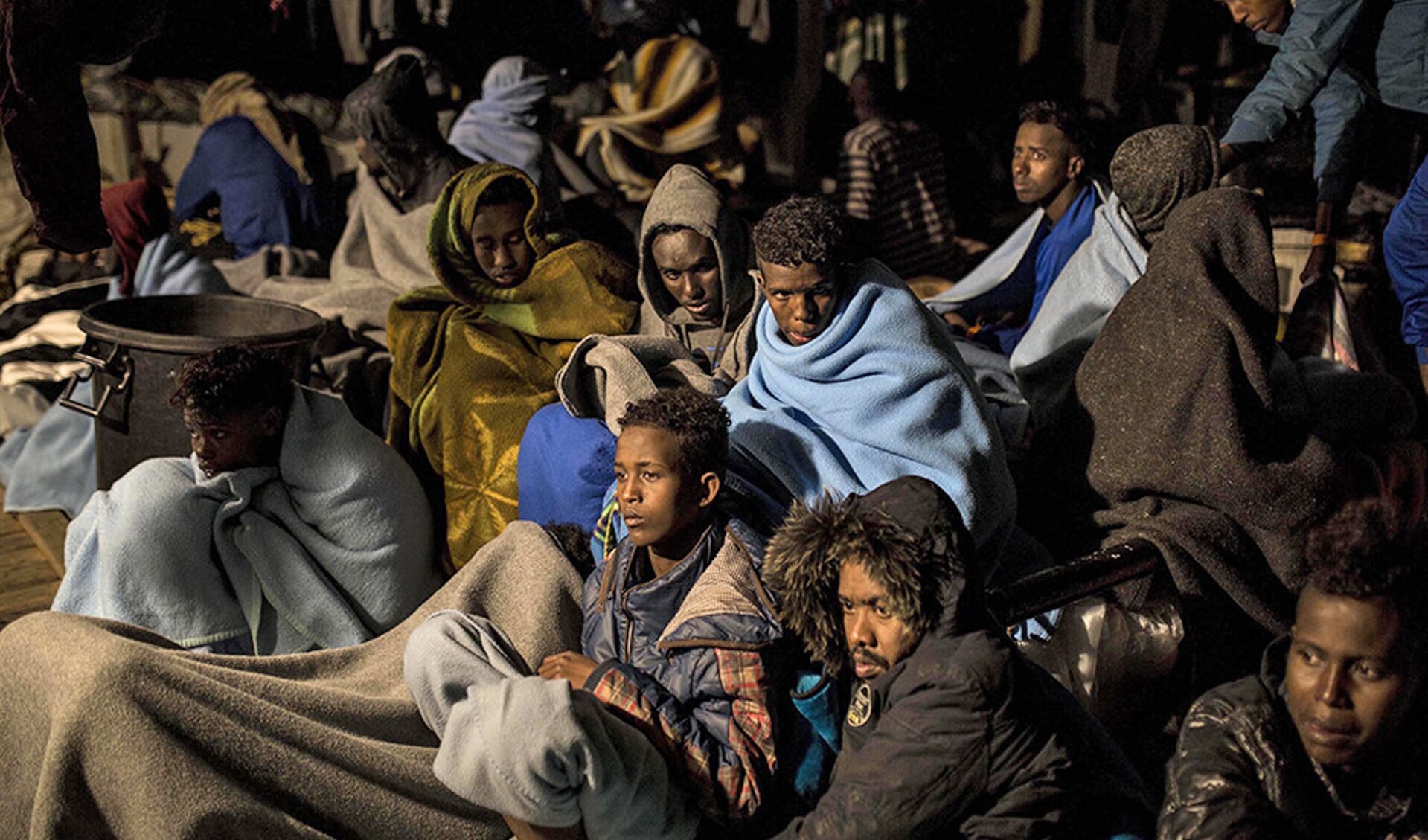 Migranten die naar Europa willen, zitten op het dek van een reddingsschip.