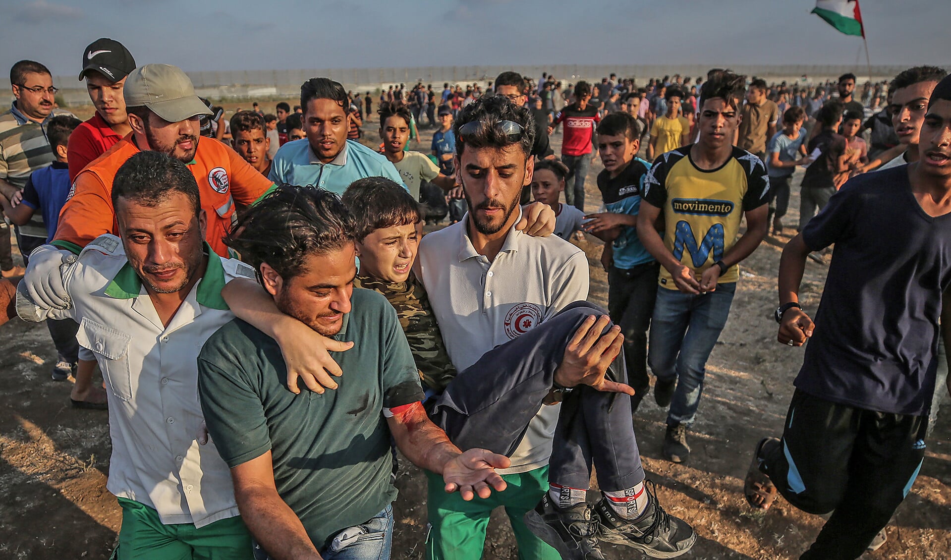 Hulpverleners in de Gazastrook dragen een gewonde jongen weg bij het grenshek met Israël. Elke vrijdag protesteren Palestijnen daar tegen Israël.