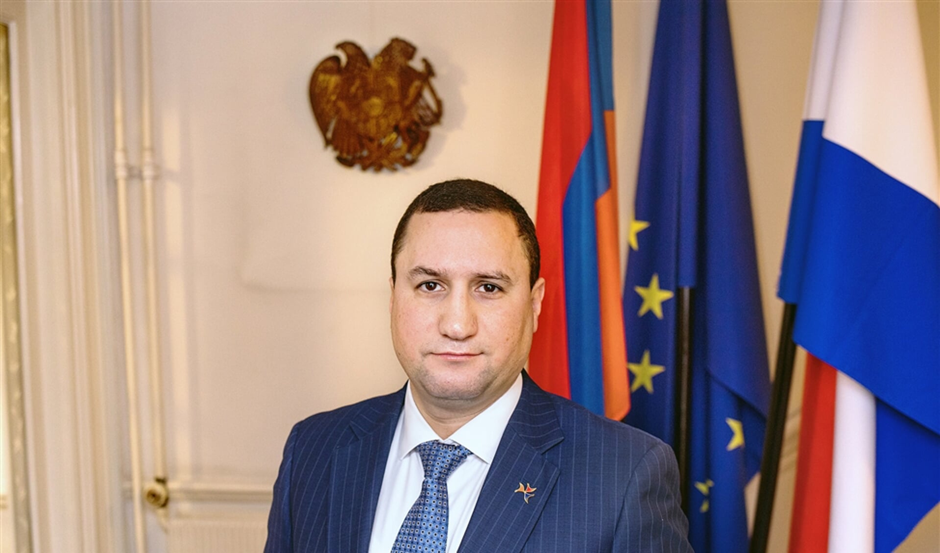 Ambassadeur Tigran Balayan van Armenië, gefotografeerd bij de Armeense, de Europese en de Nederlandse vlag.