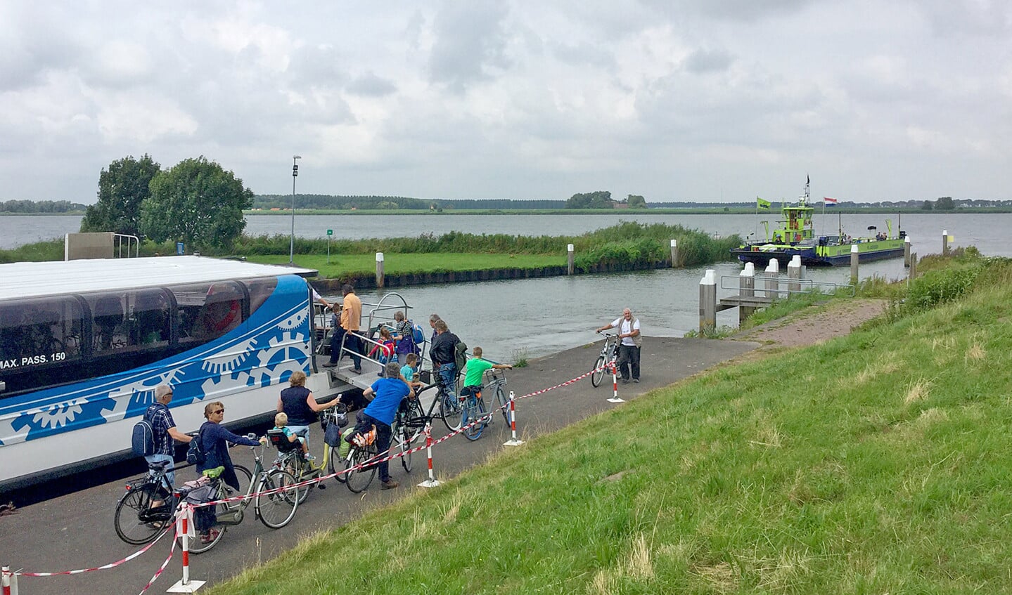 Op de voorgrond is de waterbus uit Rotterdam al aangemeerd; uiterst rechts, met fiets, gaat ook Fred Mahie naar de loopplank. Op de achtergrond nadert de veerpont die de korte, haakse oversteek zal maken naar Nieuwendijk.