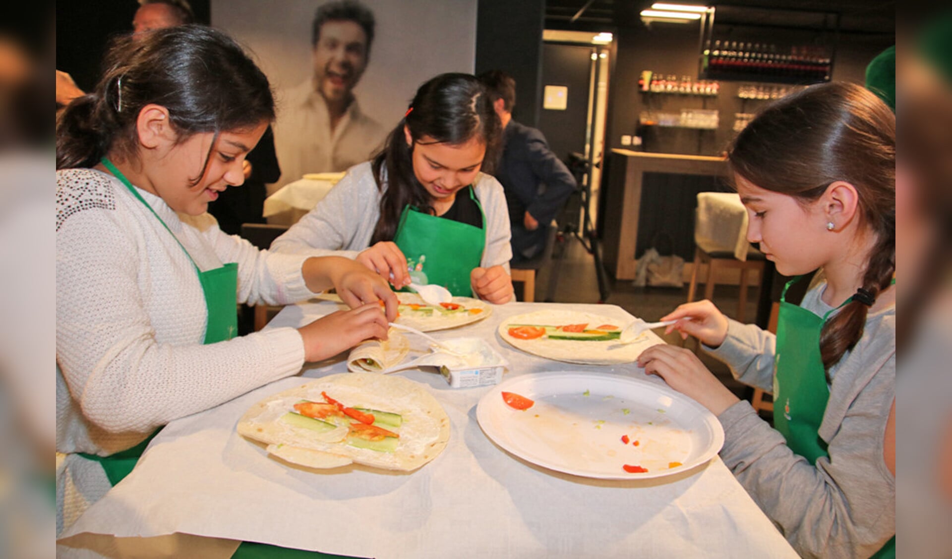 Kinderen zijn bezig met het vouwen en rollen van wraps.